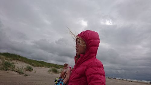 Side view of girl standing against storm clouds