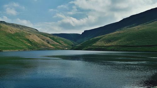 Scenic view of river by mountains against sky