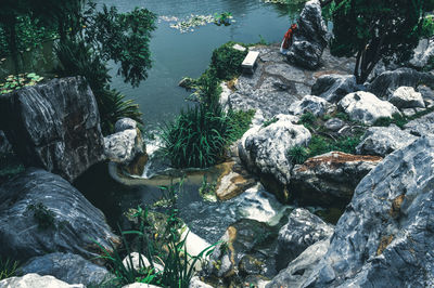 Chinese woman in national dress in chinese garden. stones, pond, waterfall