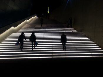 Silhouette people walking in illuminated underground walkway