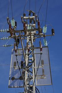 Low angle view of electricity pylon against blue sky