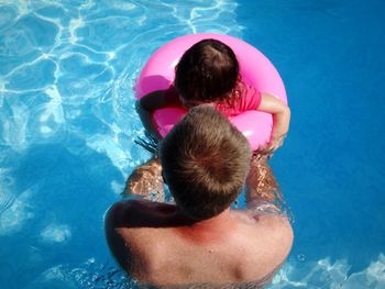 High angle view of shirtless father with daughter standing in swimming pool