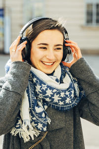 Young woman listening music on street in city