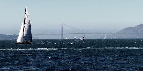 Scenic view of suspension bridge over sea against clear sky