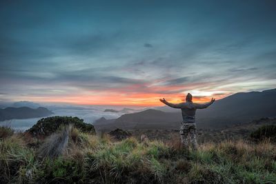 Man standing on field against sky during sunset