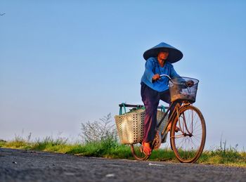 Man riding bicycle on road against clear sky