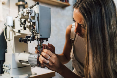 Fashion designer threading needle in sewing machine at workshop