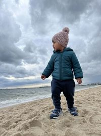 Rear view of man standing at beach against sky