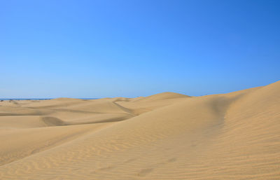 Scenic view of desert against clear blue sky