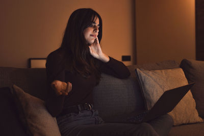 Young woman sitting on sofa at home