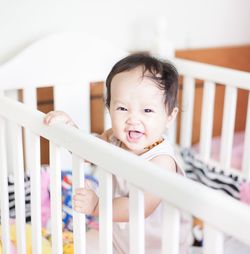 Portrait of smiling baby girl in crib at home