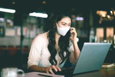 Businesswoman wearing mask using laptop at home