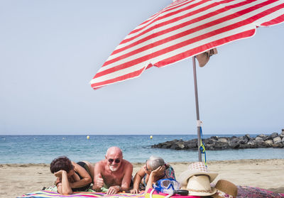 Cheerful friends at beach against clear sky