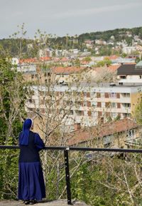 Rear view of woman standing by tree against sky