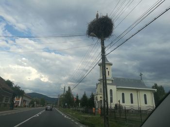 Road by electricity pylon against sky