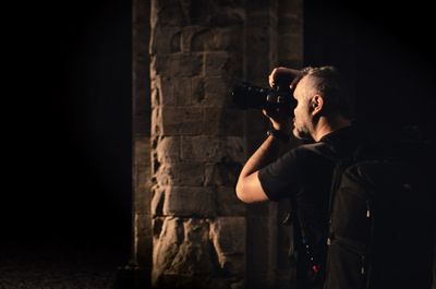 Man holding camera while standing in the dark