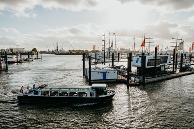 Sailboats on pier at harbor against sky