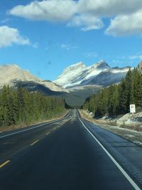 Road leading towards mountains against sky