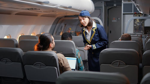 Air hostess assisting passenger in plane