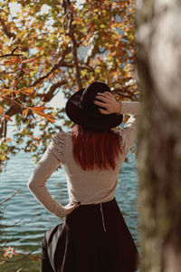 Woman wearing hat standing by tree