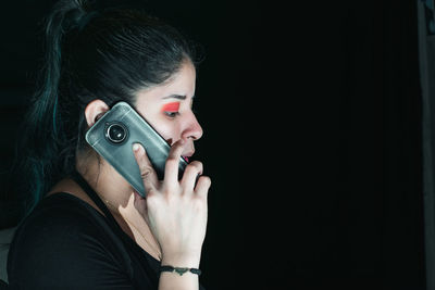 Beautiful latina woman with green hair receiving a call, with her cell phone in her hand. 