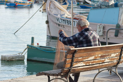 Man sitting on bench against sea