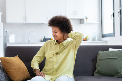Young woman sitting on sofa at home