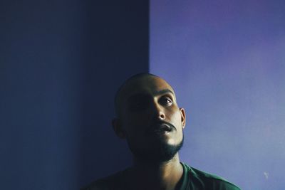 Close-up of thoughtful man against blue wall