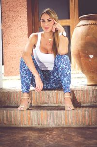 Portrait of young woman standing against wall