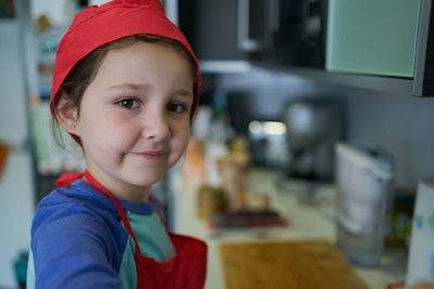 Girl in a red chef's hat is in the kitchen of her house