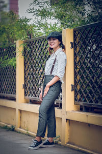 Side view portrait of woman in suspenders leaning on wall