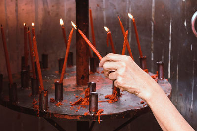 Midsection of man holding burning candles in temple