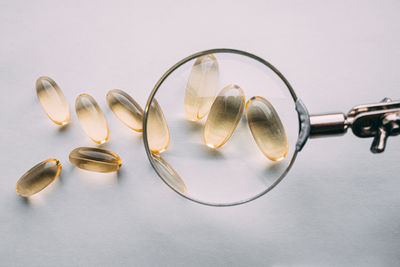 Yellow transparent omega 3 capsules under a magnifying glass. food additive development concept