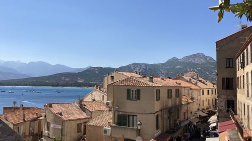 Buildings by sea against clear blue sky