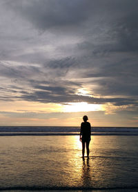 Full length of woman standing on beach against sky during sunset