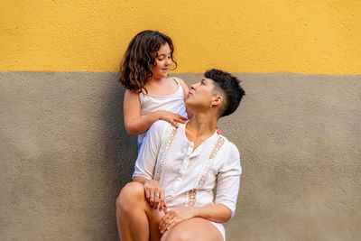 Happy woman sitting against wall