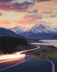 Road by snowcapped mountains against sky during sunset