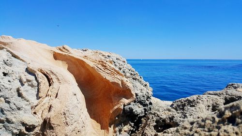 Panoramic view of rocky beach against clear blue sky