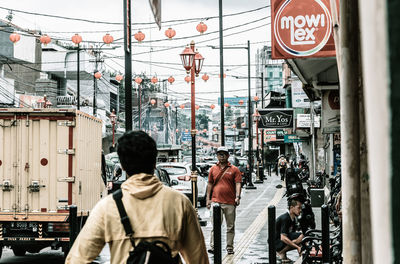 Rear view of people walking on street in city