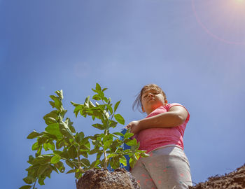 Low angle view of woman sitting on tree against clear sky