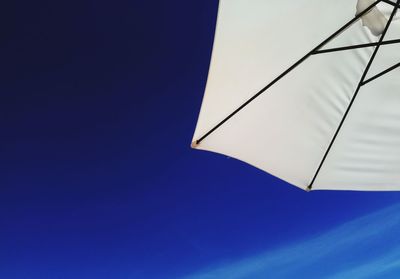 Low angle view of sunshade against clear blue sky