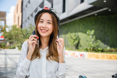 Portrait of young woman standing against building