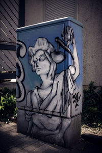 Close-up of statue against graffiti wall