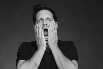 Close-up of mid adult man with mouth open against gray background