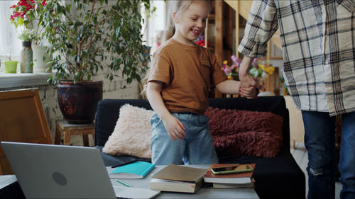 Midsection of mother holding daughter hand at home