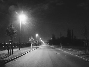 Illuminated road against sky at night