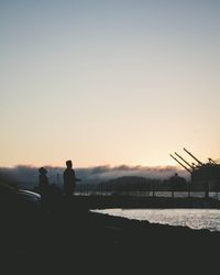 Silhouette people sitting against clear sky during sunset