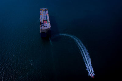 Large roro carrier vessel and tug boat sailing on the sea dramatic at night process aerial view