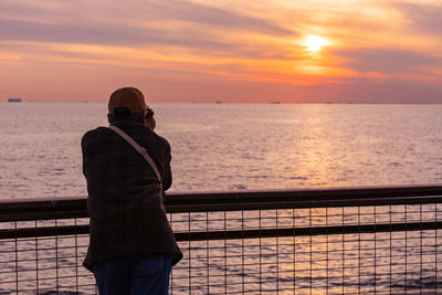 Man looking at sea against sky during sunset