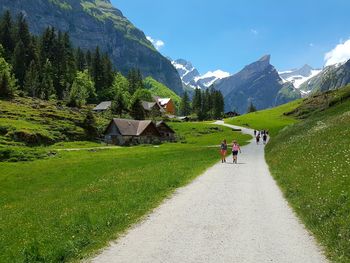 People walking on road by mountains against sky